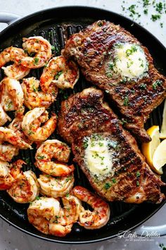 steak and shrimp in a skillet with lemon wedges