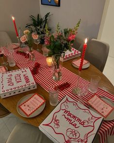 the table is set with red and white striped napkins, place mats, candles, and flowers