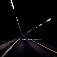 a car driving through a dark tunnel with lights at the top and bottom in the middle