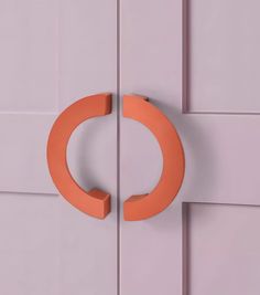 an orange circle shaped door handle on a white door with pink tiles in the background