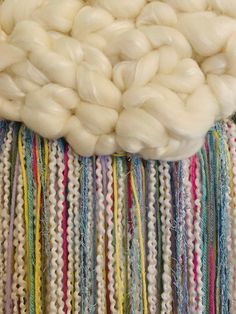 there is a large white wool ball on top of a multicolored rug with fringes