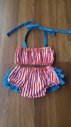 a red and white striped bathing suit laying on top of a wooden floor next to a blue string