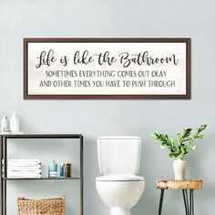 a bathroom wall hanging above a toilet with a wooden sign over it that says, life is like the bathroom sometimes everything comes out okay and other times you have to