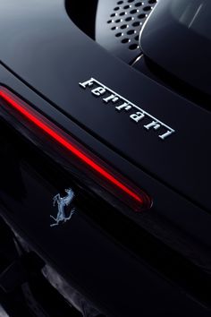 the rear end of a black sports car with it's tail lights turned on