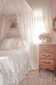 a white bed sitting next to a window in a room with flowers on the floor