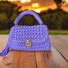 a purple crocheted purse sitting on top of a wooden table