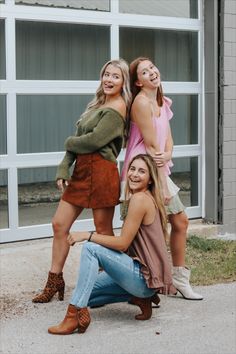 three beautiful young women posing together in front of a building