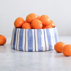 a blue and white striped bowl filled with oranges