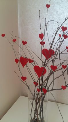 a vase filled with branches and red hearts