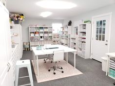 a white desk sitting in the middle of a room with lots of shelves on it