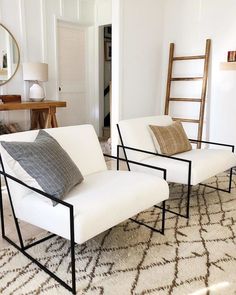 two white chairs sitting next to each other on top of a rug