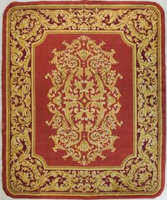 a red and gold rug with an ornate design on the center, in front of a white background