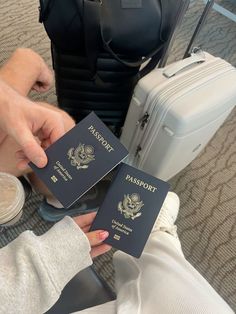 two people holding up their passports in front of some luggage