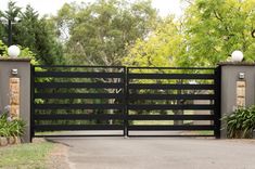 an iron gate with two gates on each side and trees in the backgroud