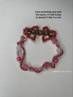 a pink beaded bracelet with hearts and words on it