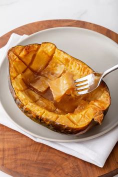 a white plate topped with an acorn covered in caramel sauce and a fork