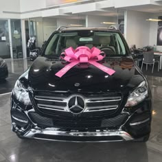 a mercedes car with a pink bow on it's front hood in a showroom