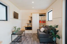 a living room filled with furniture next to a window covered in plants and bookshelves