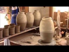 several vases sitting on top of a table in a room filled with other pottery