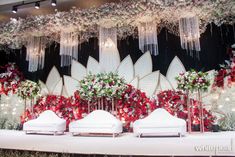 a decorated stage with white couches and red flowers