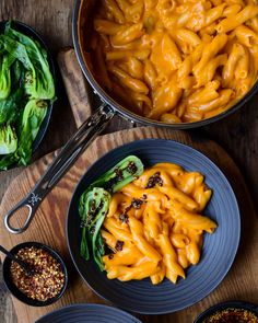 three bowls filled with macaroni and cheese on top of a wooden table