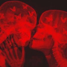 two people are kissing with red light in the background and butterflies on their heads above them