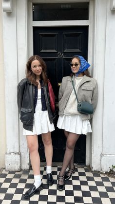 two women standing next to each other in front of a door