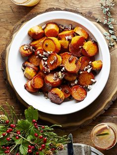 a white bowl filled with cooked potatoes on top of a wooden table next to other dishes