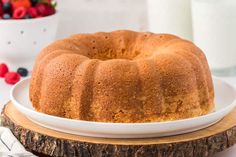 a bundt cake sitting on top of a white plate next to a bowl of strawberries