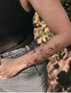 a woman's arm with flowers on it and her hand in the back pocket