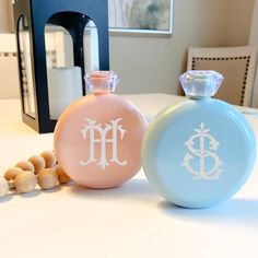 two small bottles sitting next to each other on top of a white table with beads