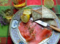 a plate topped with fish and bread next to a glass of wine