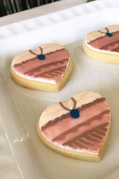 three heart shaped cookies sitting on top of a pan