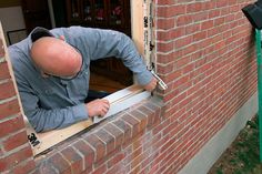 a man working on a window in a brick building