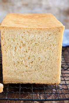 a loaf of bread sitting on top of a cooling rack next to a slice of bread