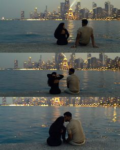 two people sitting on the ground in front of a city at night, one person kissing the other