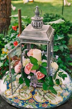 a small metal lantern sitting on top of a table covered in flowers and greenery