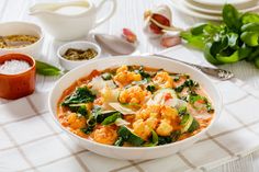 a white bowl filled with food on top of a table next to bowls and spoons