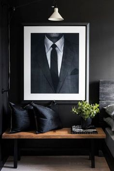 a black and white photo hanging on the wall above a wooden bench with two pillows