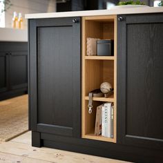 an open cabinet in the middle of a kitchen with black cabinets and white counter tops