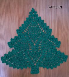 a green crocheted doily on a wooden door with a small tree in the center