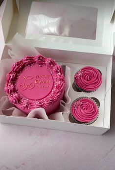 three cupcakes in a white box with pink frosting