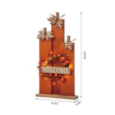 the welcome sign is decorated with wreaths and lights on an orange wooden block wall