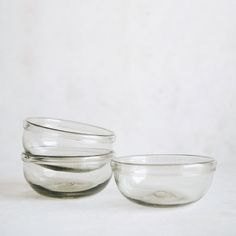 three clear glass bowls sitting on top of each other in front of a white wall