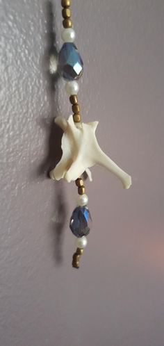 a white and gold beaded necklace hanging from a hook on a wall in a room