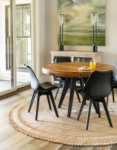 a dining room table with four chairs and a rug on the floor in front of it