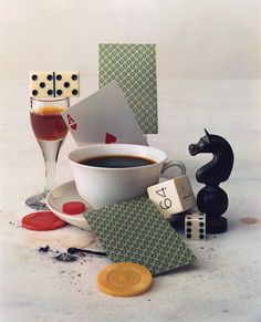 a cup of coffee next to some dice and cards