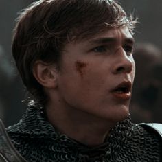 a young man in armor with blood on his face