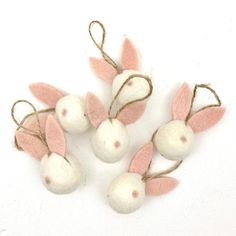 four small white and pink ornaments with twine on each ornament hanging from strings