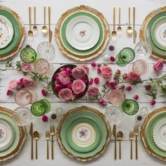 the table is set with pink roses and green plates